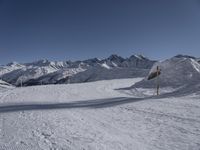 a view of a snow covered mountain range and sloped field in the foreground