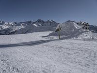 a view of a snow covered mountain range and sloped field in the foreground