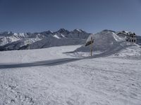 a view of a snow covered mountain range and sloped field in the foreground