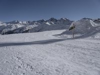 a view of a snow covered mountain range and sloped field in the foreground