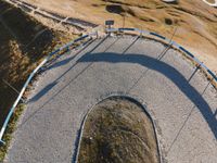 a curved road next to mountains and a sky view sign in the middle of it