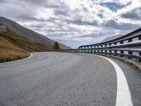 a winding road running through the mountains and hills with a long curved guard rail near it