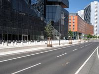 a curved road with two white lines in front of large buildings and a city sidewalk