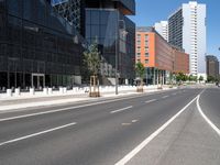 a curved road with two white lines in front of large buildings and a city sidewalk