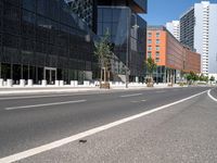 a curved road with two white lines in front of large buildings and a city sidewalk