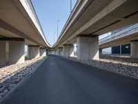 a curved road in front of several overpasses on an elevated roadway with rocks, gravel and gravel around