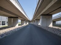 a curved road in front of several overpasses on an elevated roadway with rocks, gravel and gravel around