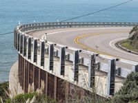 the road is curved near the beach and ocean side highway by it's sides