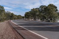 a curve in the road with trees on either side and snow on both sides and two lanes in the middle