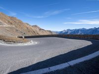 a man standing on the edge of a curve in the road on a hill top