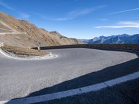 a man standing on the edge of a curve in the road on a hill top