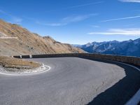 a man standing on the edge of a curve in the road on a hill top