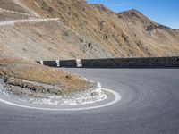 a man standing on the edge of a curve in the road on a hill top