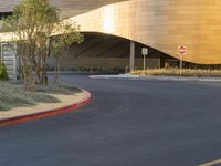 a curve road with a stop sign on one side and yellow building in the background