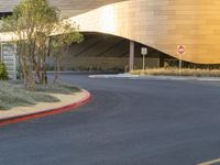 a curve road with a stop sign on one side and yellow building in the background