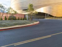 a curve road with a stop sign on one side and yellow building in the background