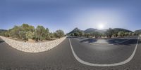 two shots show the same view of a curved road and mountain area on a sunny day