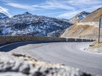 the road in front of the mountain is curved and has a sign that reads no turns