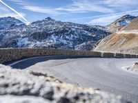 the road in front of the mountain is curved and has a sign that reads no turns