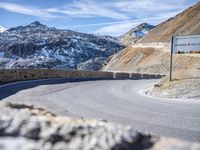 the road in front of the mountain is curved and has a sign that reads no turns