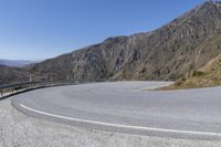 a curved road on the side of a mountain road in the middle of it are three sides are steep mountains