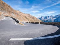 road on the side of mountain with curved curve leading to the mountains on the right