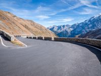 road on the side of mountain with curved curve leading to the mountains on the right