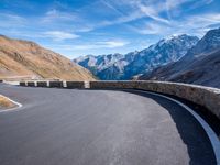 road on the side of mountain with curved curve leading to the mountains on the right