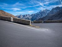 road on the side of mountain with curved curve leading to the mountains on the right