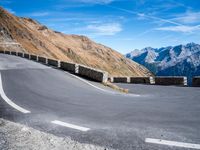 road on the side of mountain with curved curve leading to the mountains on the right
