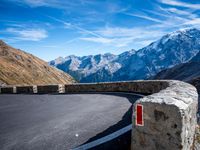 road on the side of mountain with curved curve leading to the mountains on the right