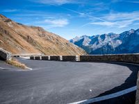 road on the side of mountain with curved curve leading to the mountains on the right