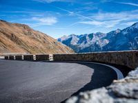 road on the side of mountain with curved curve leading to the mountains on the right