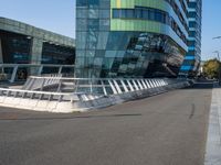 a curved road near a building with large windows on it's sides and green and blue facade