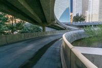 a curved road is going below two overpasses of a city with high rise skyscrapers