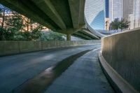 a curved road is going below two overpasses of a city with high rise skyscrapers