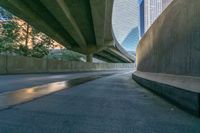 a curved road is going below two overpasses of a city with high rise skyscrapers