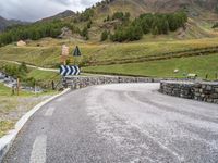 a curved road with a stone foot bridge that goes over it to the next lane