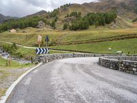 a curved road with a stone foot bridge that goes over it to the next lane