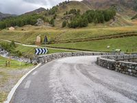 a curved road with a stone foot bridge that goes over it to the next lane