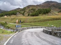 a curved road with a stone foot bridge that goes over it to the next lane