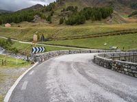 a curved road with a stone foot bridge that goes over it to the next lane