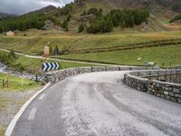 a curved road with a stone foot bridge that goes over it to the next lane