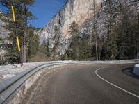 a curved road is shown surrounded by snow on the side of it, with a mountain in the background