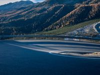 a car driving down a curved street past some mountains at sunset or sunrise or afternoon