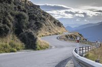 a curved road leads toward an overlook with hills in the distance and a red sign that says'climb on the top '