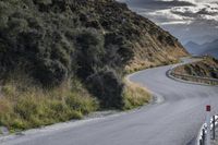 a curved road leads toward an overlook with hills in the distance and a red sign that says'climb on the top '