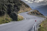 a curved road leads toward an overlook with hills in the distance and a red sign that says'climb on the top '