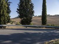 a long curved roadway through the country side with trees lining the road in front of it