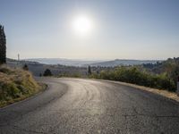 the road is curved so that a man can take this photo in the direction of the sun